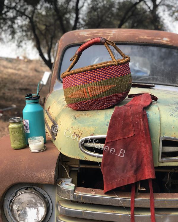 © CourtKnee.B A colorful woven basket and red apron resting on a vintage truck — © CourtKnee.B